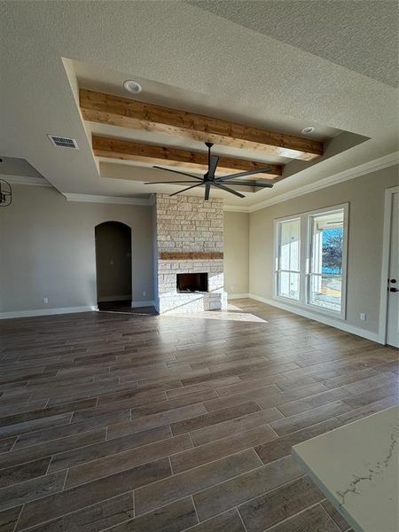 Unfurnished living room featuring a tray ceiling, a fireplace, dark wood-type flooring, and a textured ceiling