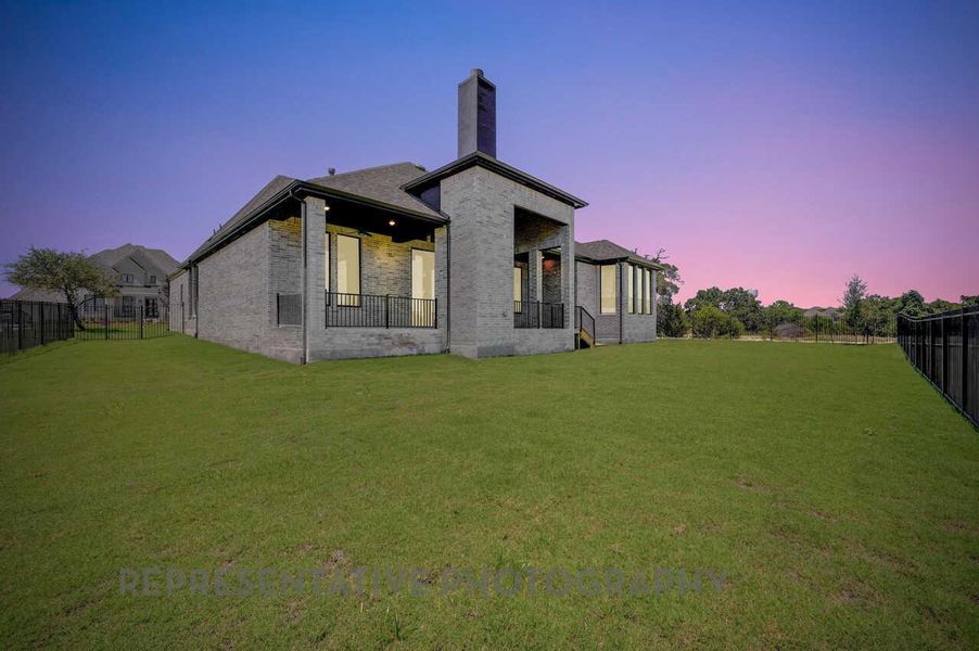 Back of property at dusk with a chimney, brick siding, and a patio area Back of property at dusk with a chimney, brick siding, and a patio area