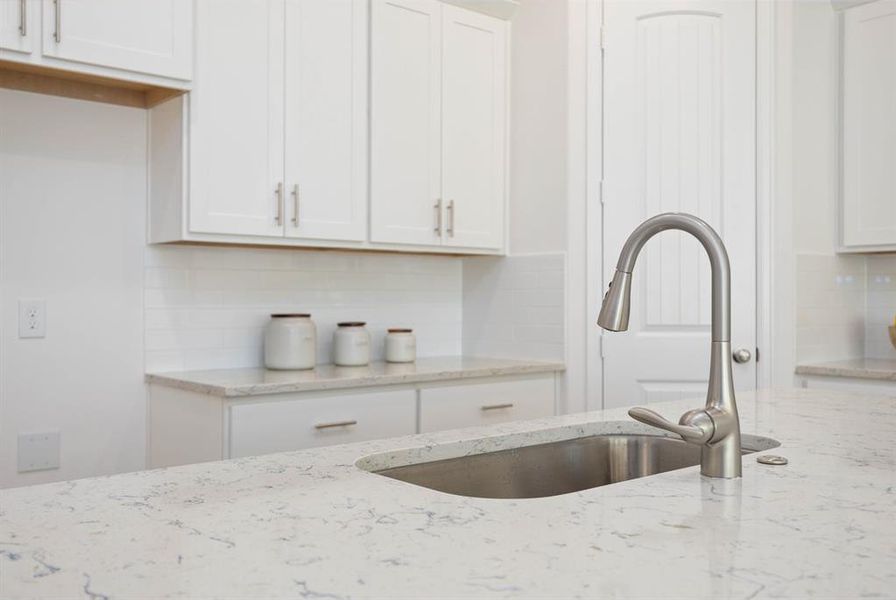 Experience luxury with quartz countertops and a sleek undermount single basin sink, complete with a brushed nickel Moen faucet and pull-down sprayer.