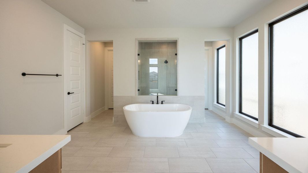 Bathroom featuring a shower stall, a freestanding bath, light tile patterned floors, vanity, and tile walls