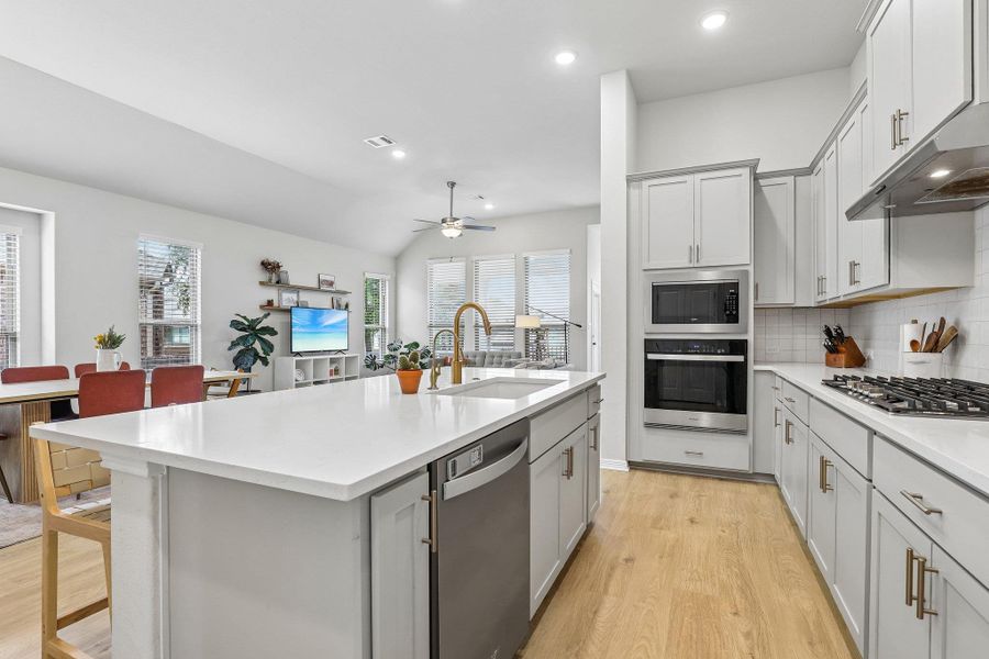A well-lit kitchen with a spacious island provides seamless flow into the living area.