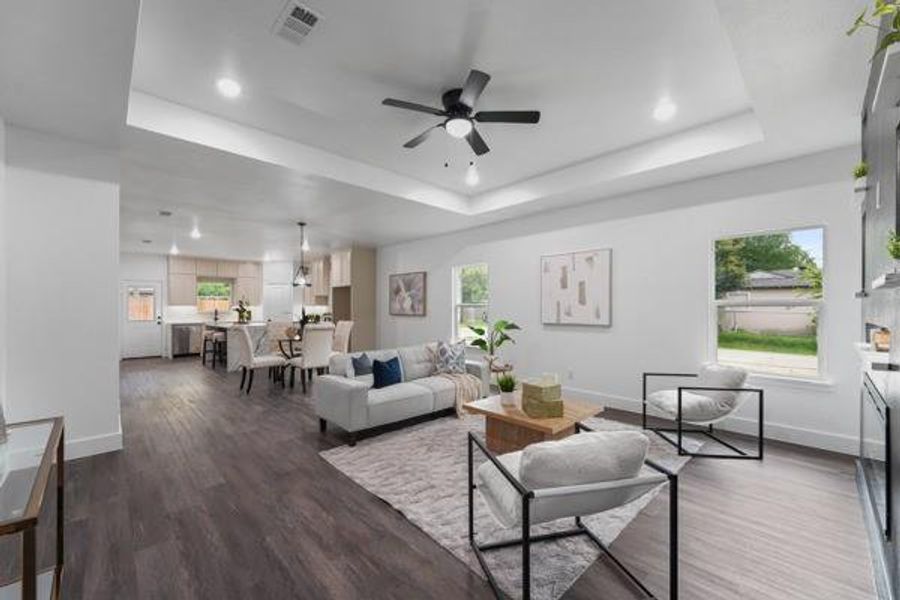 Open-concept living area featuring wood-finish flooring, recessed lighting, and a tray ceiling with a ceiling fan Open-concept living area featuring wood-finish flooring, recessed lighting, and a tray ceiling with a ceiling fan