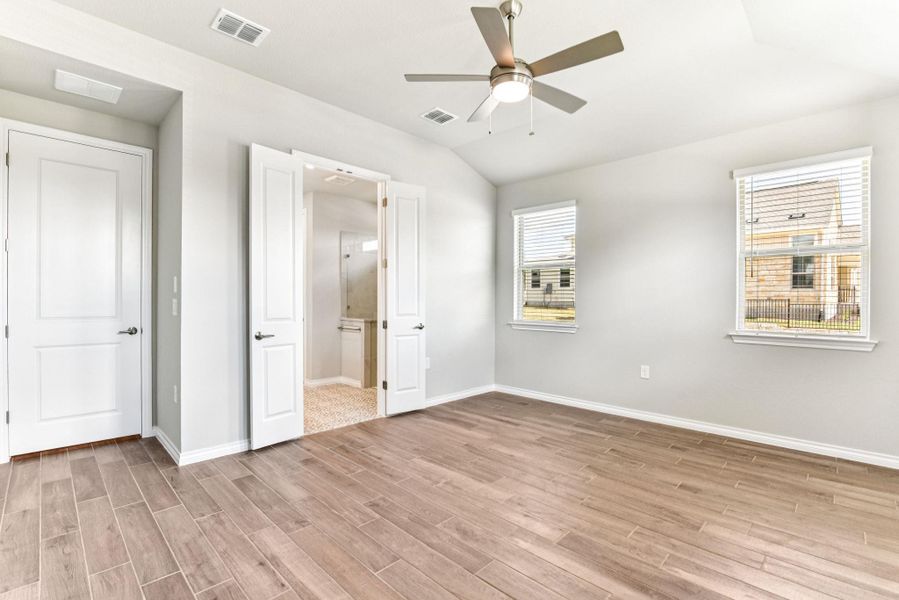 Unfurnished bedroom with connected bathroom, light wood-style flooring, lofted ceiling, and a ceiling fan Unfurnished bedroom with connected bathroom, light wood-style flooring, lofted ceiling, and a ceiling fan
