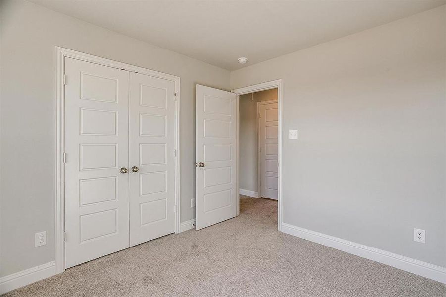 Unfurnished bedroom with light colored carpet and a closet