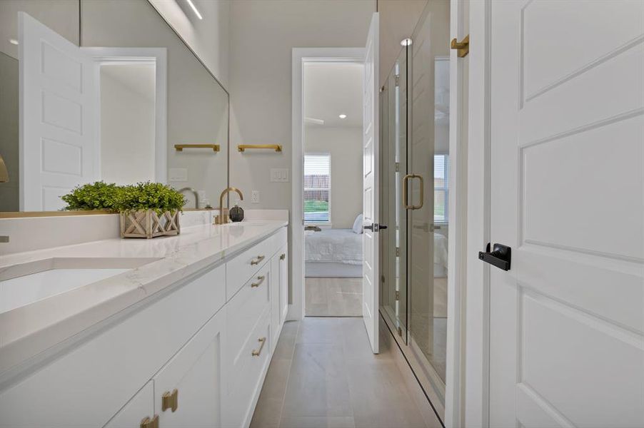 Bathroom with double vanity, connected bathroom, a shower stall, and tile patterned floors Bathroom with double vanity, connected bathroom, a shower stall, and tile patterned floors
