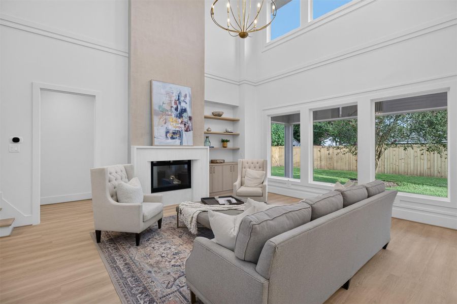 The dramatic two-story living room features impressive 20-foot ceilings, expansive windows, a designer fireplace, and custom built-ins that create a warm yet sophisticated gathering space. The dramatic two-story living room features impressive 20-foot ceilings, expansive windows, a designer fireplace, and custom built-ins that create a warm yet sophisticated gathering space.