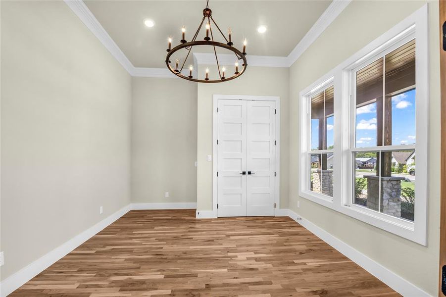 Unfurnished dining area with wood finished floors, crown molding, a chandelier, and recessed lighting