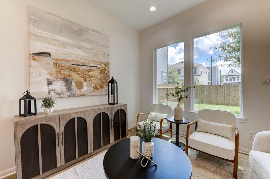 Living room with hardwood floors, high ceilings, recessed lighting, matte black chandelier, floor-to-ceiling windows with backyard views, rear exit door, and open sightline to dining area.