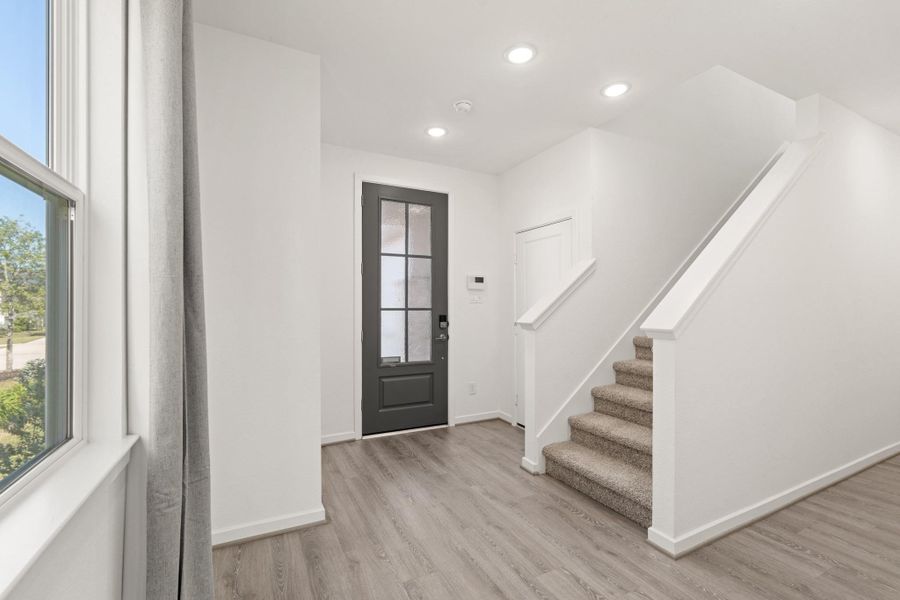 Heading back to the front of the home, you see another view of the bright entryway. Upstairs leads to the secondary bedrooms and bathroom.