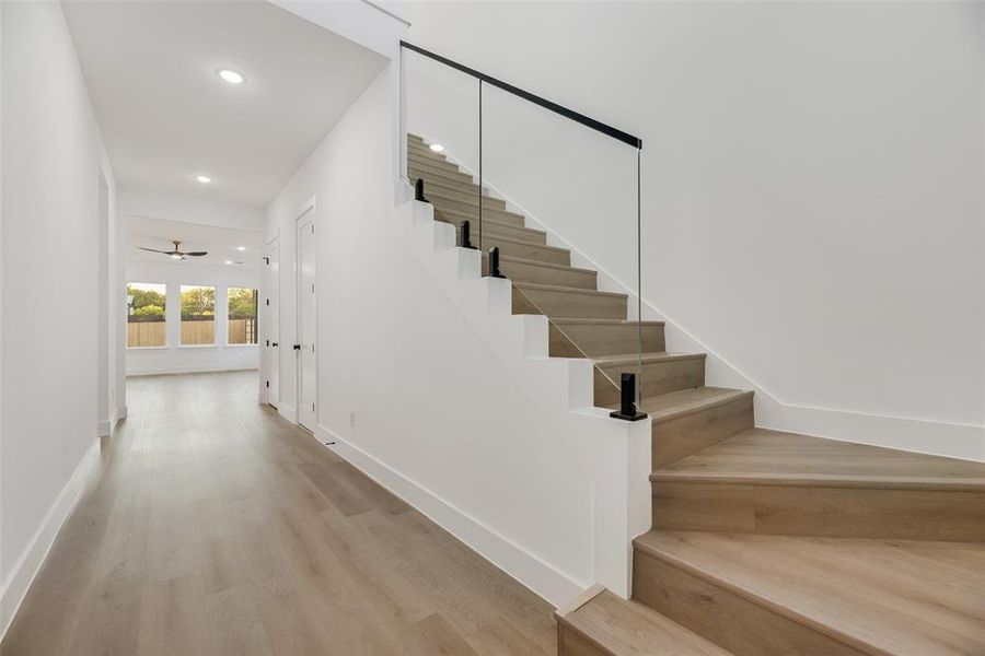 Staircase featuring wood finished floors, a ceiling fan, and recessed lighting