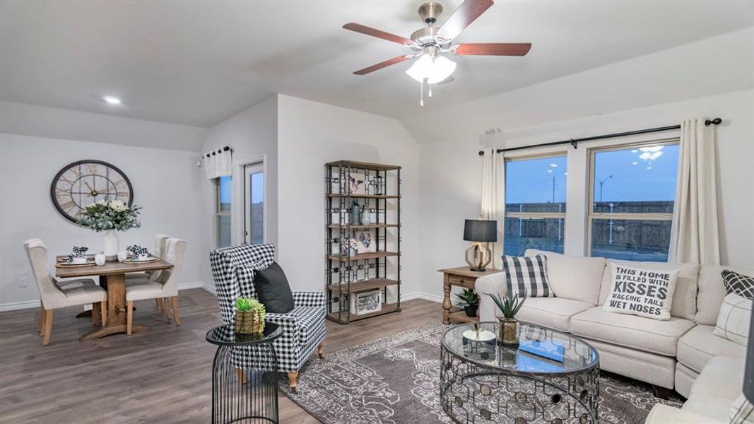 Living room with wood finished floors, vaulted ceiling, and a ceiling fan Living room with wood finished floors, vaulted ceiling, and a ceiling fan