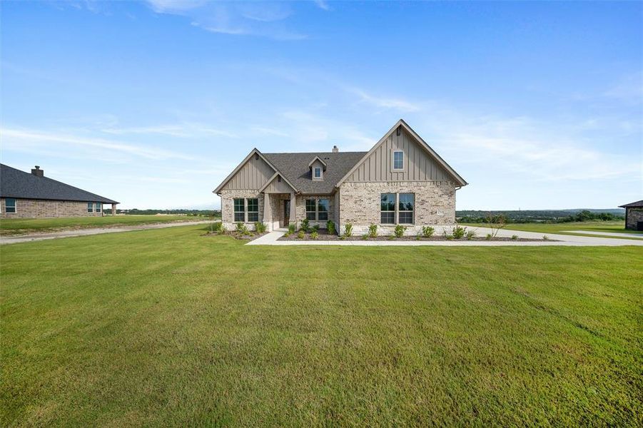 View of front facade featuring board and batten siding, a front yard, and brick siding View of front facade featuring board and batten siding, a front yard, and brick siding