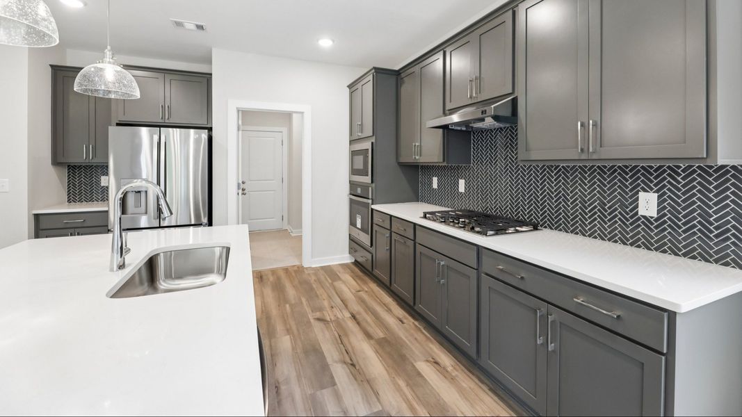 Kitchen with hard surface flooring, quartz countertops, and pendant lighting Kitchen with hard surface flooring, quartz countertops, and pendant lighting
