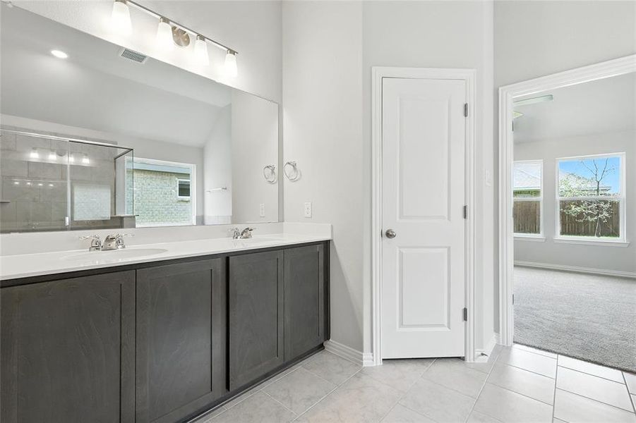 Bathroom with double vanity, tile patterned floors, and a shower with door