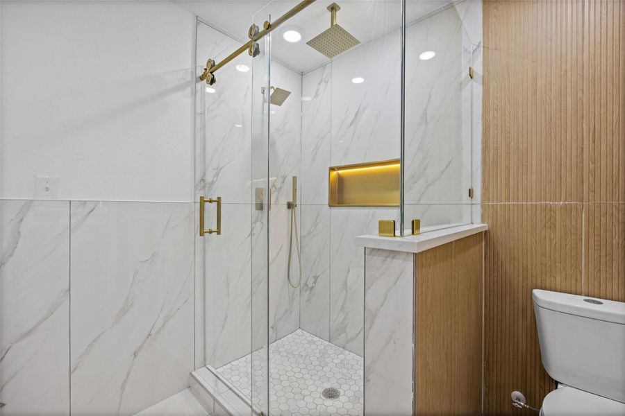 Contemporary shower enclosure featuring clear glass panels with gold-finish hardware Contemporary shower enclosure featuring clear glass panels with gold-finish hardware