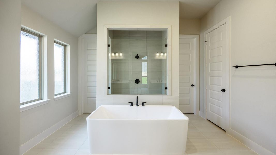 Full bathroom with a soaking tub, plenty of natural light, tiled shower, and baseboards Full bathroom with a soaking tub, plenty of natural light, tiled shower, and baseboards