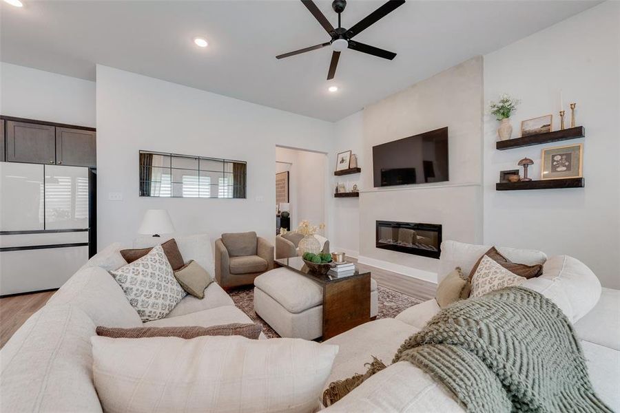 Living area featuring a modern linear fireplace, mounted television, and floating shelves