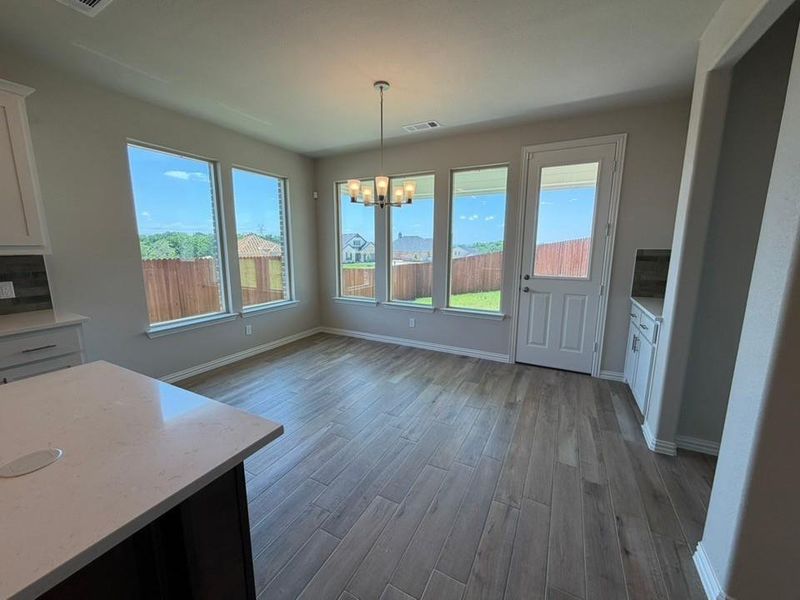 Spacious dining area featuring wood-look plank flooring, multiple windows, and a glass-paneled door