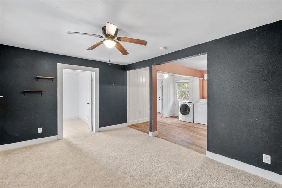 Unfurnished bedroom featuring ceiling fan, independent washer and dryer, and light colored carpet