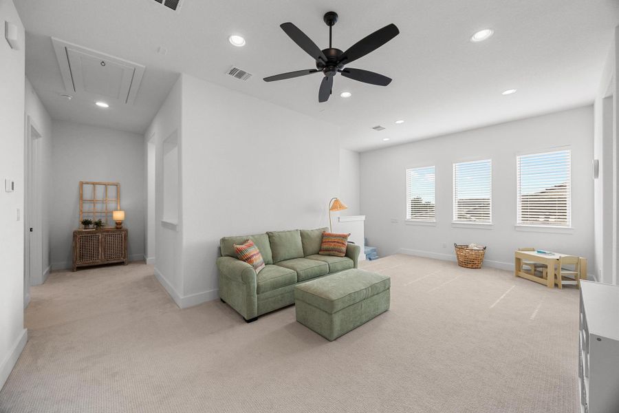 Carpeted living room featuring attic access, recessed lighting, and a ceiling fan
