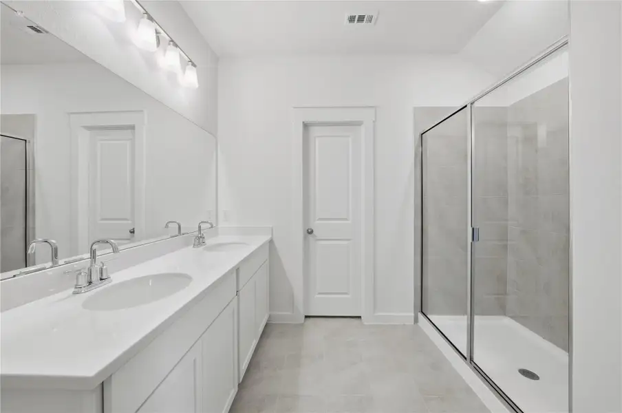 Bathroom with a stall shower, double vanity, and light tile patterned floors Bathroom with a stall shower, double vanity, and light tile patterned floors
