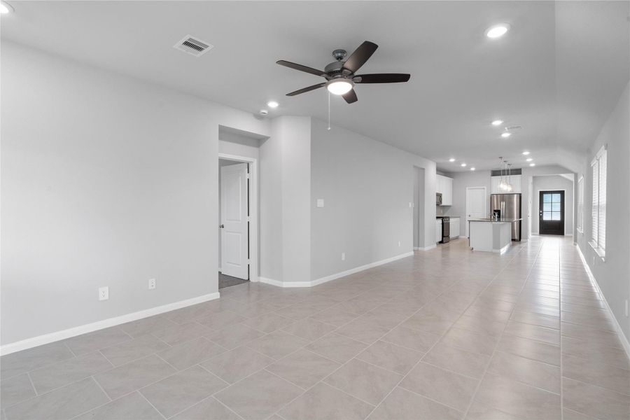 This expansive view from the back of the house showcases a seamless, open-concept layout that creates a warm and inviting path for guests, drawing the eye past the heart of the home toward the welcoming front entryway
