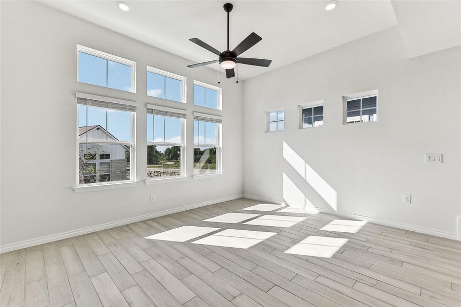 Unfurnished room featuring a towering ceiling, baseboards, recessed lighting, a ceiling fan, and wood finished floors Unfurnished room featuring a towering ceiling, baseboards, recessed lighting, a ceiling fan, and wood finished floors