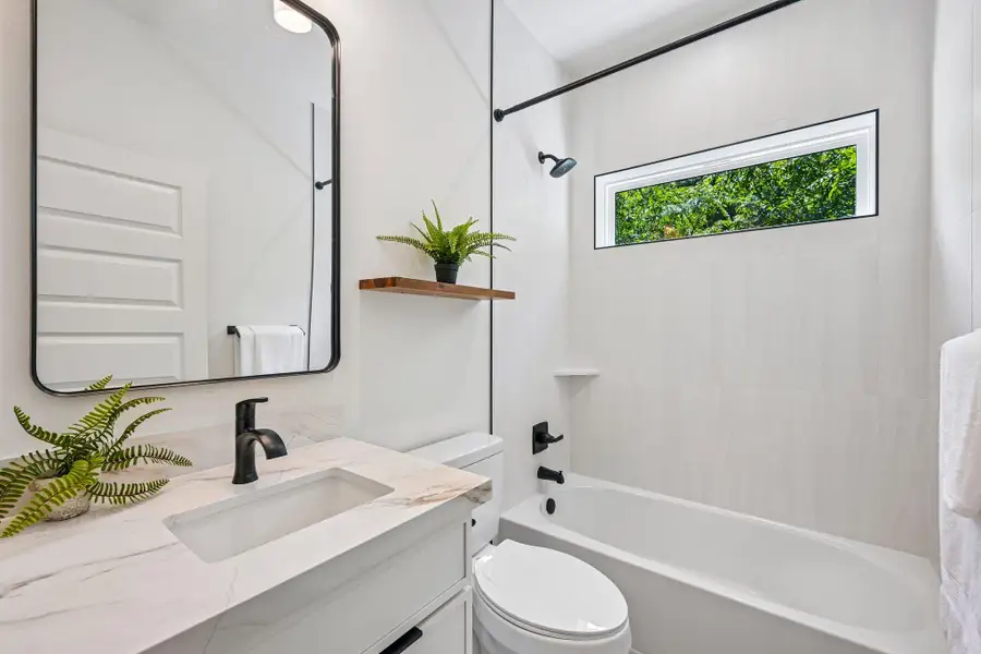Sleek vanity with modern fixtures and a window overlooking lush greenery defines this pristine bathroom. Sleek vanity with modern fixtures and a window overlooking lush greenery defines this pristine bathroom.