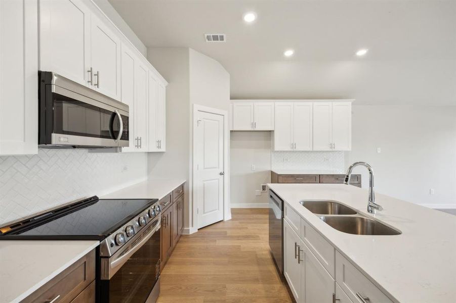 Kitchen featuring white cabinets, stainless steel appliances and a sink in the island