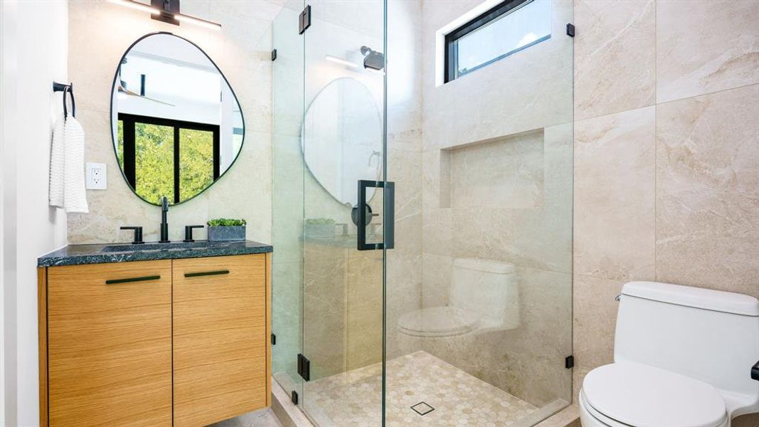 Bathroom featuring tile walls, walk in shower, vanity, and toilet