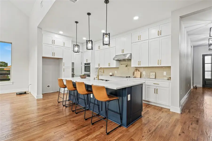 Kitchen featuring under cabinet range hood, white cabinetry, light countertops, backsplash, and recessed lighting Kitchen featuring under cabinet range hood, white cabinetry, light countertops, backsplash, and recessed lighting