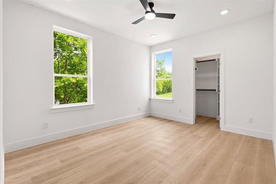 The room features light wood flooring, white walls, and a black ceiling fan with an integrated light