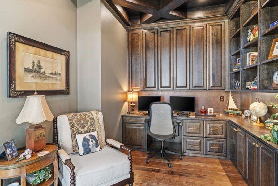 Office area with built in study area, light wood-style flooring, coffered ceiling, and beam ceiling