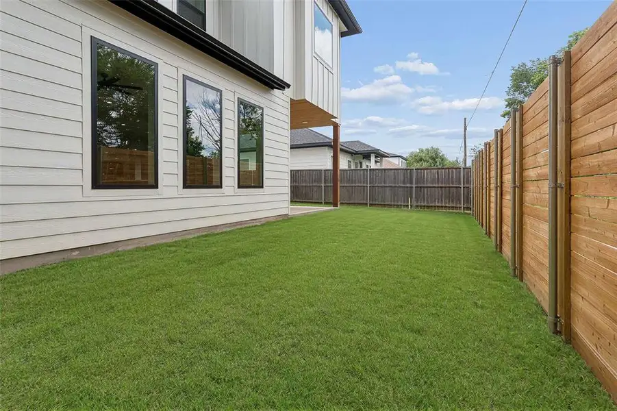 Spacious grassy yard defined by a new wood plank privacy fence. Spacious grassy yard defined by a new wood plank privacy fence.