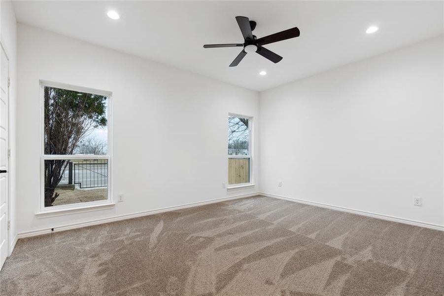 Carpeted empty room with a wealth of natural light and ceiling fan