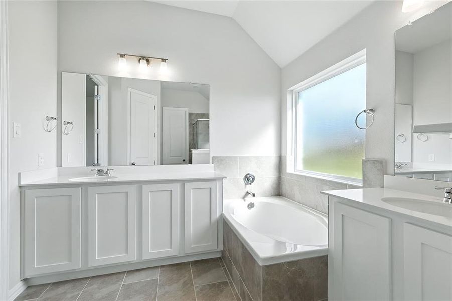 Full bath featuring two vanities, a bath, a stall shower, lofted ceiling, and light tile patterned flooring Full bath featuring two vanities, a bath, a stall shower, lofted ceiling, and light tile patterned flooring