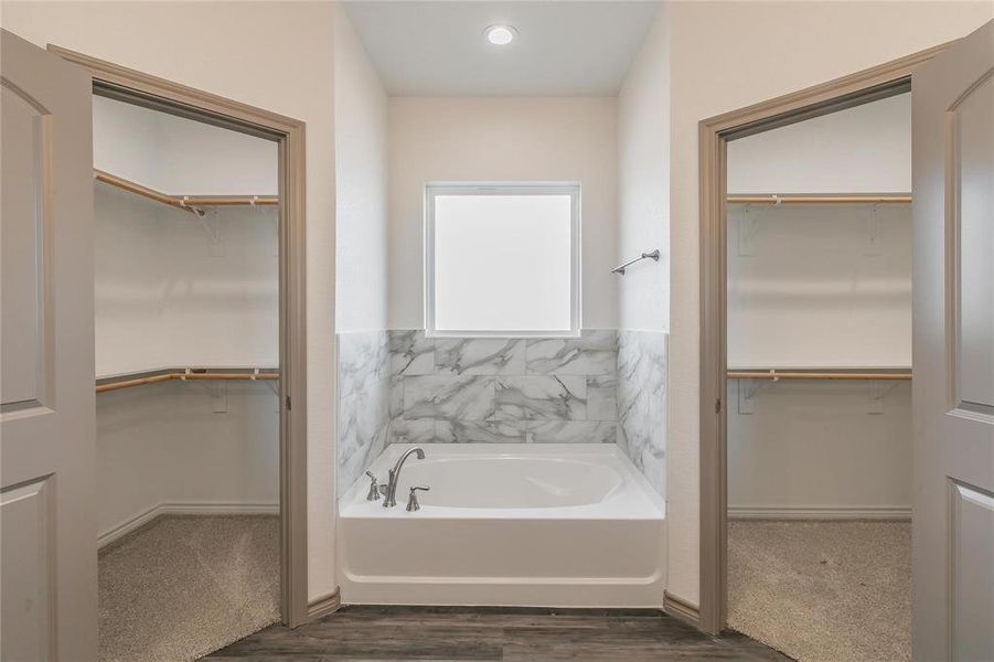 Bathroom with a walk in closet and a garden tub