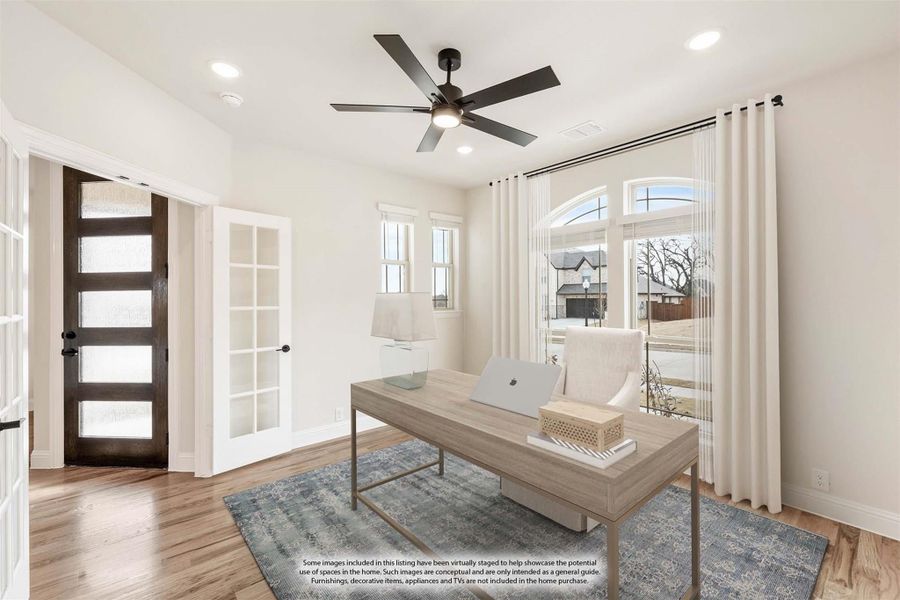 Home office with wood desk, ceiling fan, French doors, and hardwood floors in a bright white room