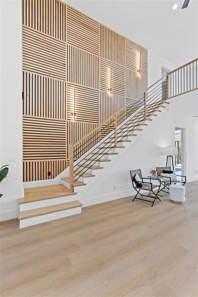 Stairway featuring wood finished floors and a towering ceiling
