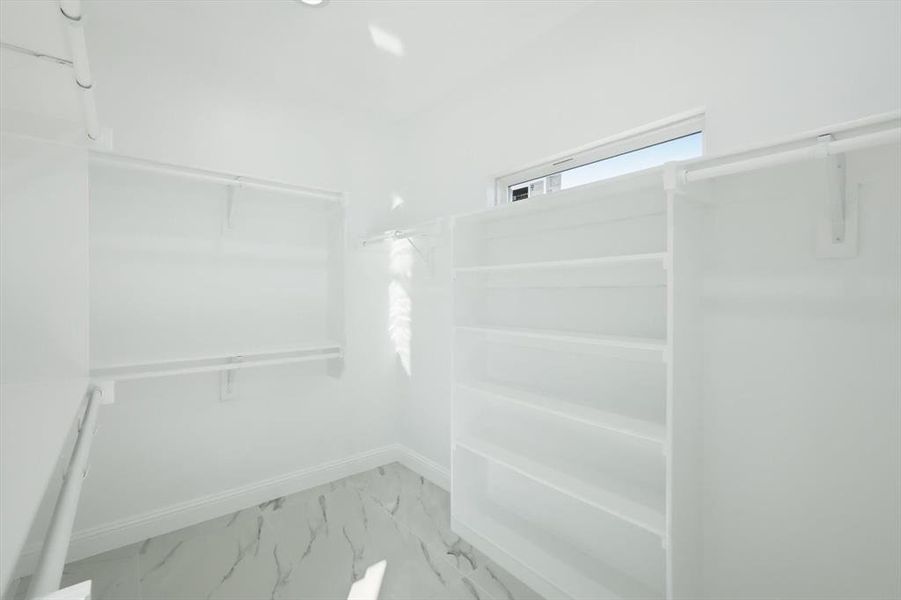 Spacious closet featuring light marble finish floors