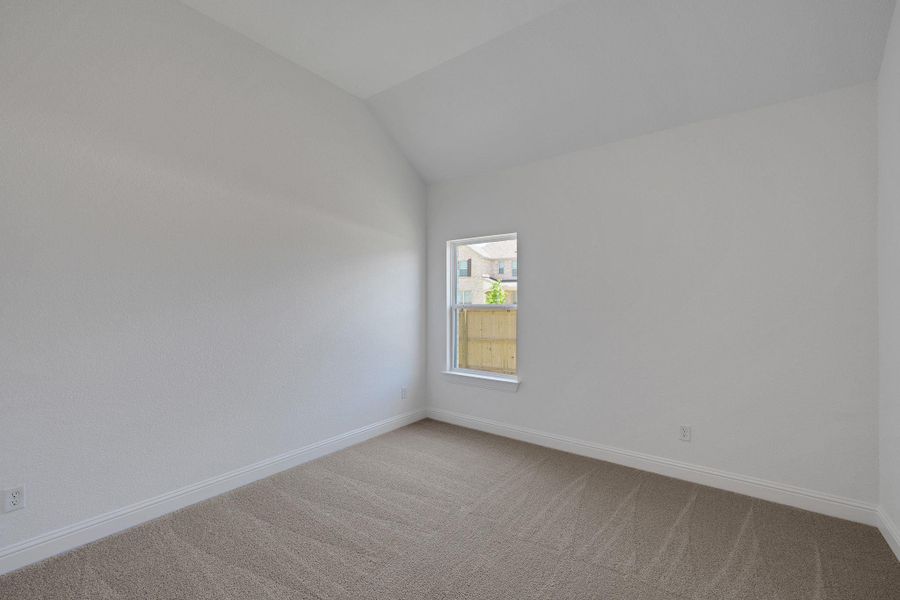 Carpeted spare room with vaulted ceiling and baseboards