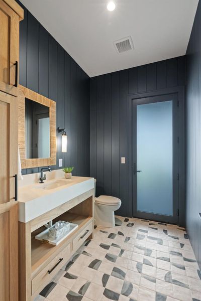 Half bathroom featuring vanity, wood walls, and light tile patterned floors