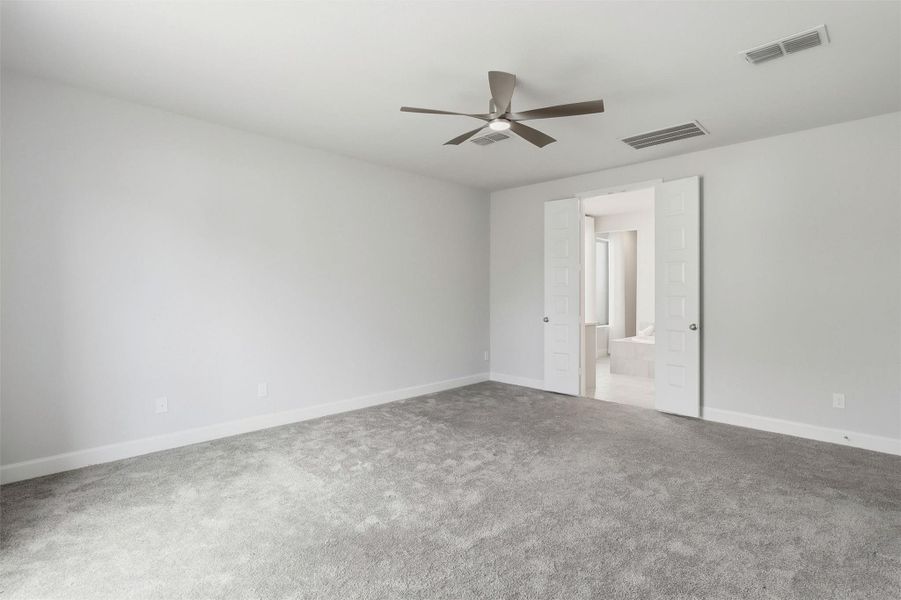 From this perspective, the primary bedroom showcases its impressive scale and thoughtful layout. Double doors lead directly into the luxurious ensuite bath, creating a seamless private retreat.