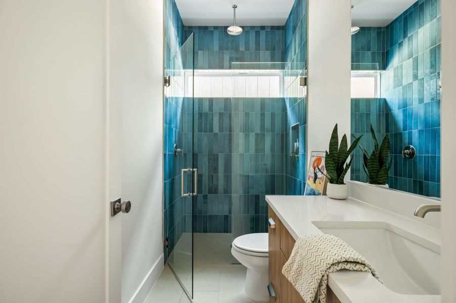 Stylish bathroom with a glass-enclosed shower, featuring striking blue tile work and a clean vanity. Stylish bathroom with a glass-enclosed shower, featuring striking blue tile work and a clean vanity.