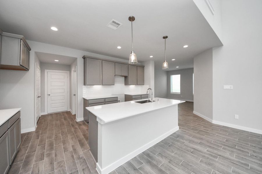 This generously spacious kitchen is a dream realized! With a massive granite island, high ceilings, soft close cabinets, granite countertops, stainless steel appliances, a sleek tile backsplash, recessed lighting, and an extended counter area, it offers both style and practicality. All this opens up to the expansive family room, creating a perfect hub for gatherings. Sample photo of completed home with similar floor plan. Actual colors and selections may vary.