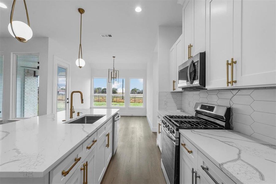Kitchen featuring appliances with stainless steel finishes, recessed lighting, white cabinetry, backsplash, and wood finished floors Kitchen featuring appliances with stainless steel finishes, recessed lighting, white cabinetry, backsplash, and wood finished floors