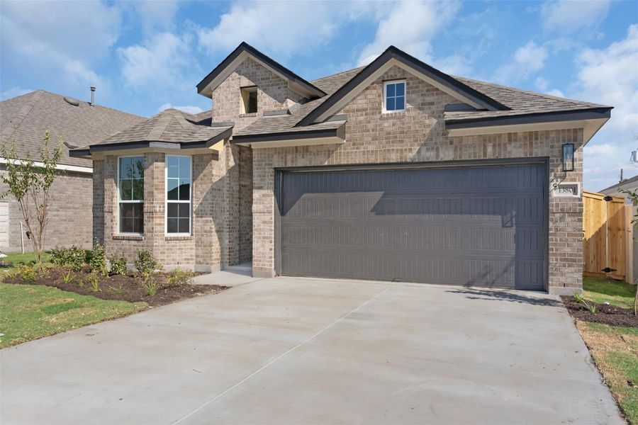 French country style house with brick siding, concrete driveway, roof with shingles, and an attached garage