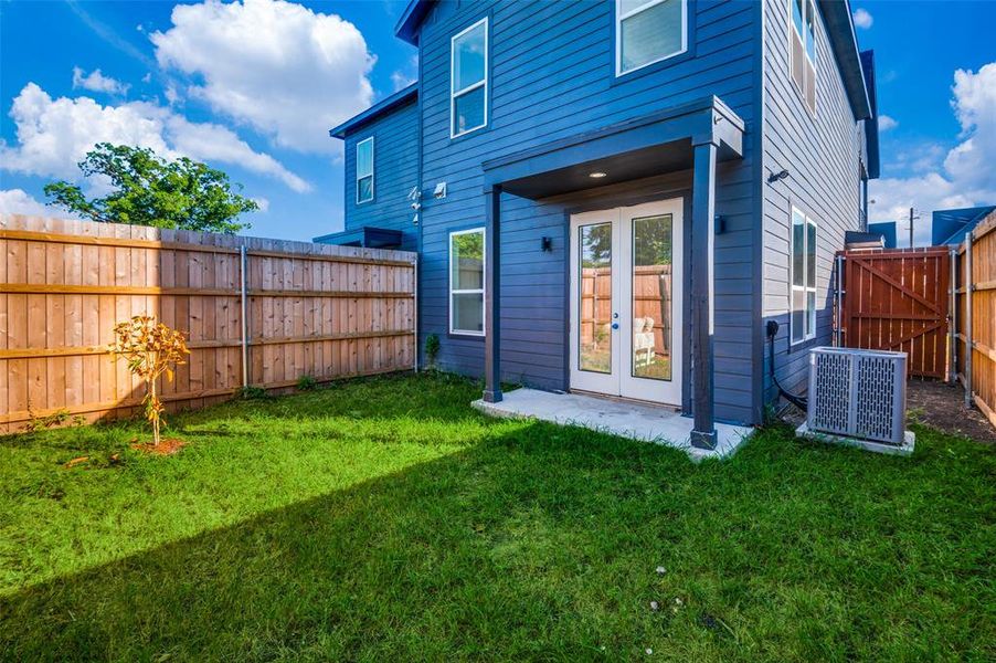 Back of house with central AC unit, french doors, and a lawn