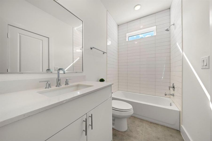 The downstairs full bathroom with a quartz countertop And neutral finishes.