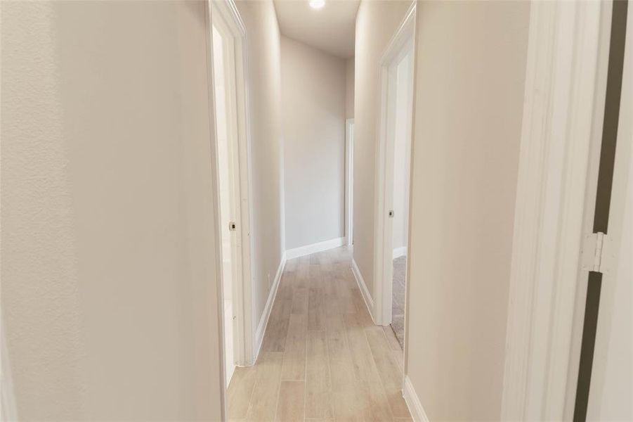 Hall to 4 additional bedrooms with light tile like hardwood / wood-style floors